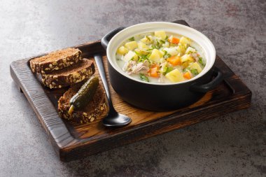 Ogorkowa Polonya Ekşi Turşu Çorbası ahşap tepsideki tencereye yakın çekim. Yatay