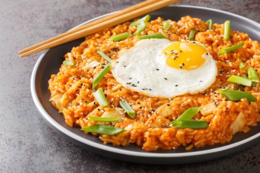 Ev yapımı kimchi pilavı. Üstünde de masanın üstündeki tabakta yumurta kaplaması var. Yatay