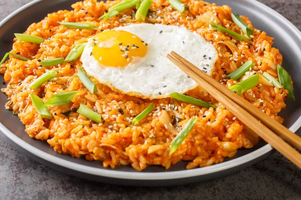 Kimchi fried rice with fried egg on top and chopsticks for eating Korean food closeup on the plate on the table. Horizonta