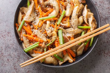 Asya usulü kızartılmış istiridye ve havuçlu shiitake mantarı, susam tohumu ve yeşil soğan masaya yakın bir tabakta baharatlı sos. Yukarıdan yatay üst görünüm