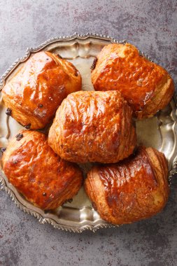 Pain au chocolat, dikdörtgen, mayalı hamur ve çikolata damlalarının birleşiminden oluşan bir Fransız viennoizerie rulosudur. Yukarıdan dikey üst görünüm