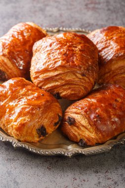 Pain au chocolat, dikdörtgen, mayalı hamur ve çikolata damlalarının birleşiminden oluşan bir Fransız viennoizerie rulosudur. Dikey