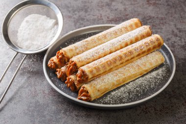 Koyu arka planda kaynamış yoğunlaştırılmış sütle lezzetli gofret ruloları. Yatay