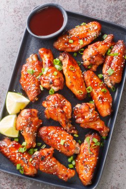 Yapışkan tavuk kanatları, masanın üstündeki tabağa yakın soslu. Yukarıdan dikey üst görünüm