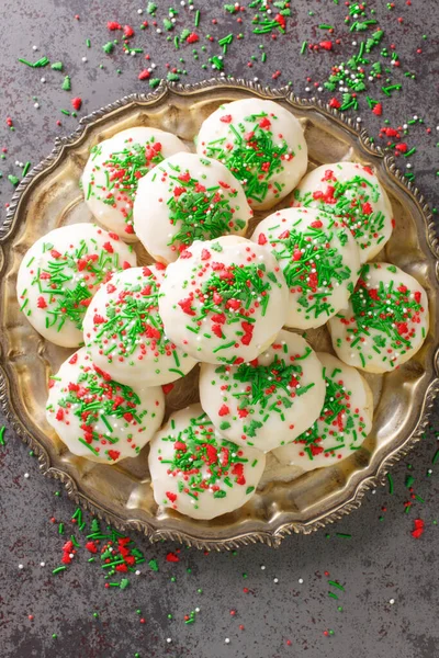 Italian sprinkle cookies are delicious, soft cookies dunked into a sweet glaze and topped with colorful sprinkles closeup in the plate on the table. Vertical top view from abov