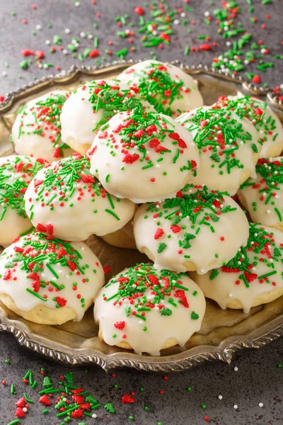 Italian sprinkle cookies are delicious, soft cookies dunked into a sweet glaze and topped with colorful sprinkles closeup in the plate on the table. Vertica