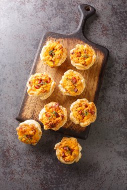 Yumurta, peynir ve jambonla doldurulmuş taze pişmiş hamur tatlısı bardakları masadaki tahta tahtaya yakın plan. Yukarıdan dikey üst görünüm