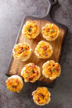 Cheddar and Ham Quiche Cups masadaki tahta tahtaya yakın çekim. Yukarıdan dikey üst görünüm
