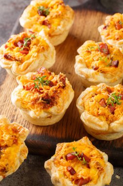 Cheddar and Ham Quiche Cups masadaki tahta tahtaya yakın çekim. Dikey