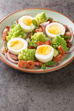 Romanesco lahanası, haşlanmış yumurta, kızarmış domuz pastırması ve masada yakın plan mikro yeşillikler. Dikey