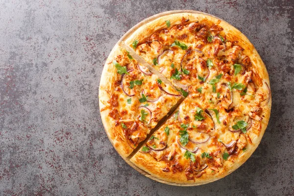 BBQ Chicken Pizza is such a classic with its sweet, tangy, and salty BBQ sauce, bits of juicy chicken, cheese, and savory onions closeup on the wooden board on the table. Horizontal top vie