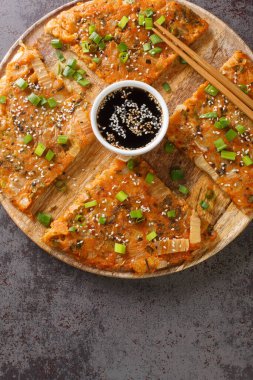 Kore usulü kimçi krep Kimchijeon sosuyla servis edilir ve masaya susam ve yeşil soğan serpiştirilir. Yukarıdan dikey üst görünüm