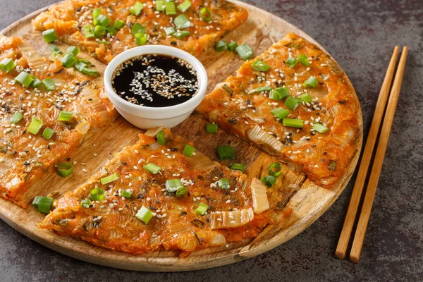 stock image Kimchi-buchimgae or kimchijeon made with sliced kimchi, flour batter and sometimes other vegetables closeup on the wooden board on the table. Horizonta