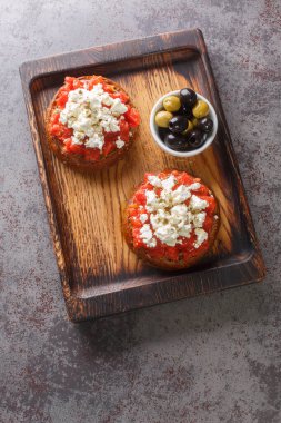 Dakos Girit Meze aperatifi, arpa ezmesi, domates, peynir, kekik otu ve zeytinyağı. Masanın üzerindeki ahşap tahtaya yakın plan. Yukarıdan dikey üst görünüm