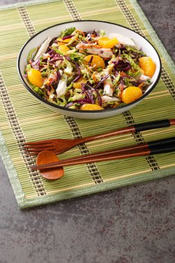 Çin esinlenilmiş mandalinalı tavuk salatası, kırmızı lahana, Çin lahanası, havuç ve erişte masanın üzerindeki kaseye yakın. Dikey