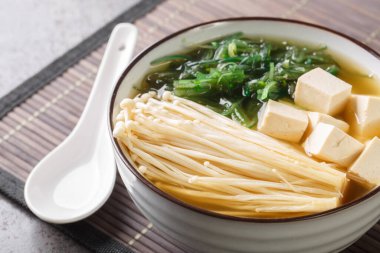 Enoki Miso Çorbası, tofu peyniri ve deniz yosunuyla yakın plan, masanın üstünde. Yatay