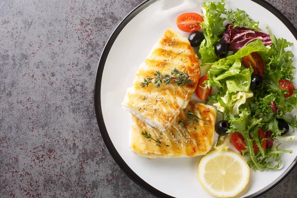 テーブルの上のプレートにトマト オリーブ レタスミックスとレモンのクローズアップの新鮮なサラダとおいしい健康的な焼きタラ魚 Abovからの水平方向のトップビュー — ストック写真