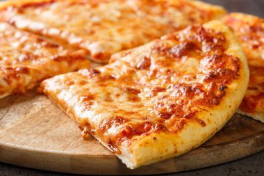 Eritilmiş peynirli ve taban domates soslu lezzetli çıtır New York usulü pizza masanın üzerinde tahtaya yakın plan. Yatay