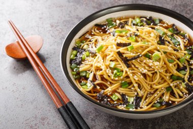 Memil Guksu Soğuk Soba Eriştesi çorbası, deniz yosunu, yeşil soğan ve susam tohumları. Masanın üzerindeki kaseye yakın çekim. Yatay