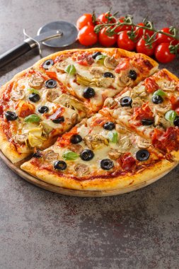 Capricciosa enginarlı, zeytinli, jambonlu ve mantarlı klasik bir pizza masanın üzerindeki tahta tahtaya yakın plan. Dikey