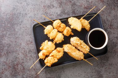 Kushikatsu kushiage Japonya 'dan geleneksel bir yemektir. Masanın üzerindeki tabakta şiş, ekmek ve kızarmış yakın plan parçalardan oluşur. Yukarıdan yatay üst görünüm