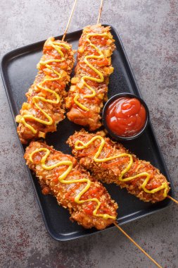 Kore mısırı sosislileri hamura bulanmış sosisli sandviçler, sonra da bol yağda kızartılmış ve masada duran şeker hardalı ve ketçapla bitirilmiş. Yukarıdan dikey üst görünüm