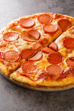 Sehpanın üzerinde sosis, peynir ve domates sosuyla dilimlenmiş baharatlı pizza. Dikey