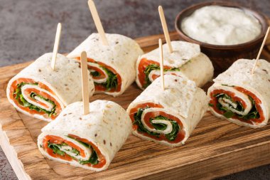 Somon filetosu, krem peynir ve otlardan oluşan aperatifler masanın üzerindeki tahta tahtaya yakın planda. yatay