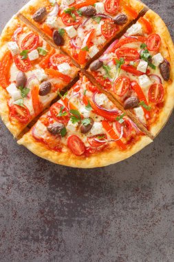 Fresh Homemade Vegetarian Greek Pizza with feta and vegetables closeup on the wooden board on the table. Vertical top view from abov