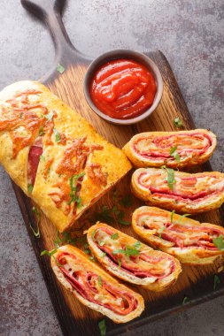 Stromboli Pizza homemade dough loaded with meats, sauce and cheese and rolled up and baked closeup on the wooden board on the table. Vertical top view from abov