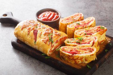 Italian stromboli, delicious pizza roll filled with sausage and ham closeup on the wooden board on the table. Horizonta