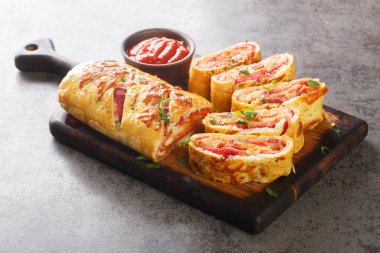 Hot Italian stromboli roll stuffed with salami sausage and mozzarella cheese close-up on a wooden board on the table. horizonta