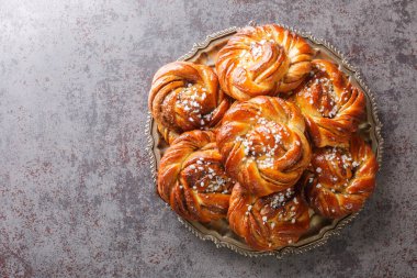 Swedish cinnamon rolls kanelbullar topped with pearl sugar close-up on a plate on the table. Horizontal top view from abov