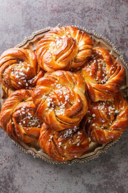 Swedish kanelbullar cinnamon buns made with a perfectly soft and chewy cardamom dough, a buttery cinnamon-sugar filling, and twisted into cute little knots close-up. Vertical top view from abov