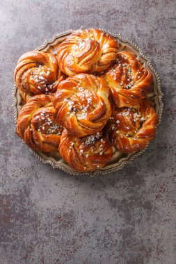 Cinnamon roll or kanelbulle is a famous Swedish pastry close-up on a plate on the table. Vertical top view from abov