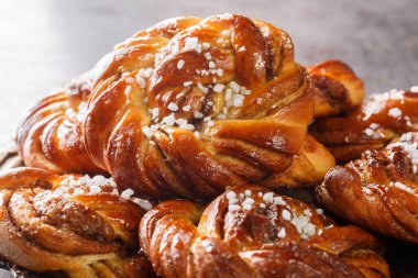 Swedish kanelbullar cinnamon buns made with a perfectly soft and chewy cardamom dough, a buttery cinnamon-sugar filling, and twisted into cute little knots close-up on a plate. Horizonta