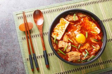 Sundubu Jjigae or soft tofu stew, is a traditional Korean dish made with silky soft uncurdled tofu coated in a spicy and flavorful broth closeup on the bowl. Horizontal top view from abov clipart