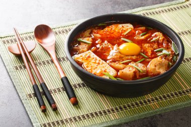 Spicy soft tofu stew with kimchi and pork belly  closeup on the bowl on the table. Horizonta
