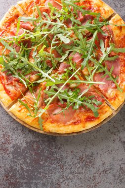 Delicious pizza with prosciutto and arugula closeup Italian snacks. Vertical top view from abov