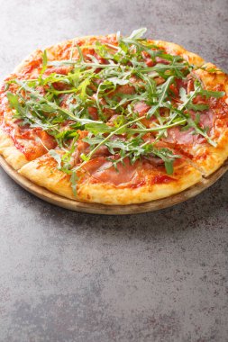 Prosciutto Pizza with cheese, tomato sauce and fresh arugula close-up on a wooden board on the table. Vertica