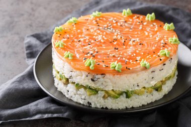 Sushi cake with a salmon, rice, avocado and philadelphia cheese closeup on the plate on the table. Horizonta