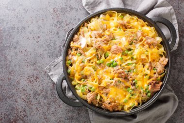 Homemade Cheesy Tuna Casserole with Peas and Egg Noodles closeup on the pan on the table. Horizontal top view from abov
