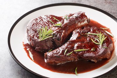Delicious drunken pork chops fried and then cooked with red wine, herbs and spices close-up on a plate on the table. Horizonta