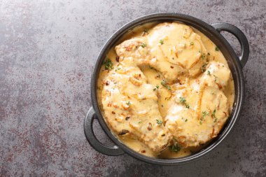 Fried spicy pork chops and then braised in creamy onion gravy closeup on the pan on the table. Horizontal top view from abov