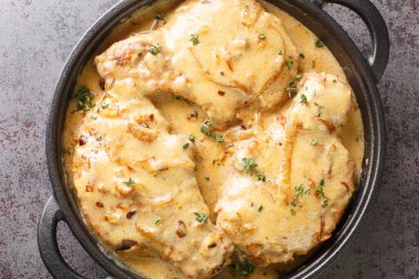Homemade Smothered Bone-In Pork Chops in creamy onion gravy closeup on the pan on the table. Horizontal top view from abov