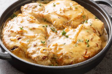 Homemade Smothered Bone-In Pork Chops in creamy onion gravy closeup on the pan on the table. Horizonta