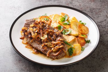 Original and Authentic German Zwiebelrostbraten with onion gravy and fried potatoes Bratkartoffeln closeup on the plate on the table. Horizonta