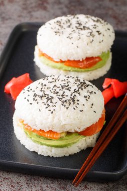 Sushi burger with avocado and a salmon on a dark background. Selective focus. Vertica