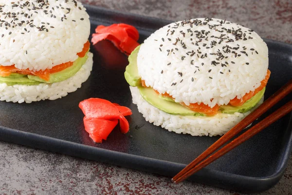 Japanese style Sushi sandwich with rice, salmon, avocado and sesame close-up on a plate on the table. Horizonta