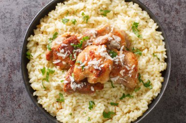 Delicious chicken risotto with parmesan and garlic closeup on the plate on the table. Horizontal top view from abov